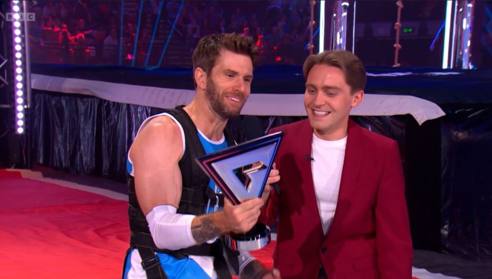 BBC iPlayer screenshot showing a man holding a trophy, with another man beside him.