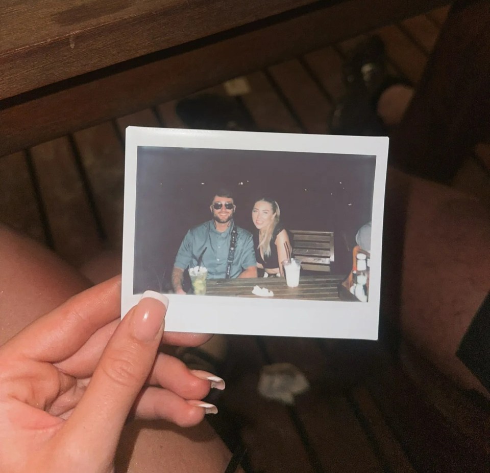 Instant photo of a couple sitting at a table outdoors at night.