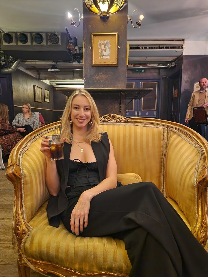 Woman sitting in an ornate chair, holding a drink.