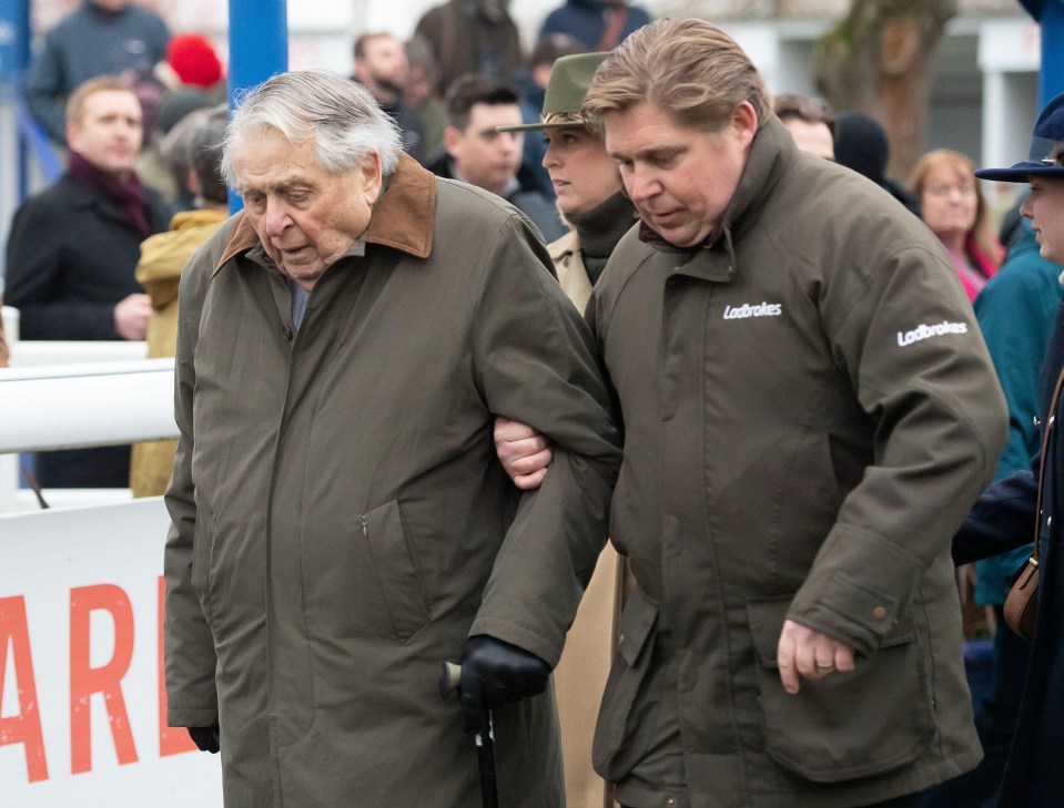 John Hales being assisted by a man after a horse race.