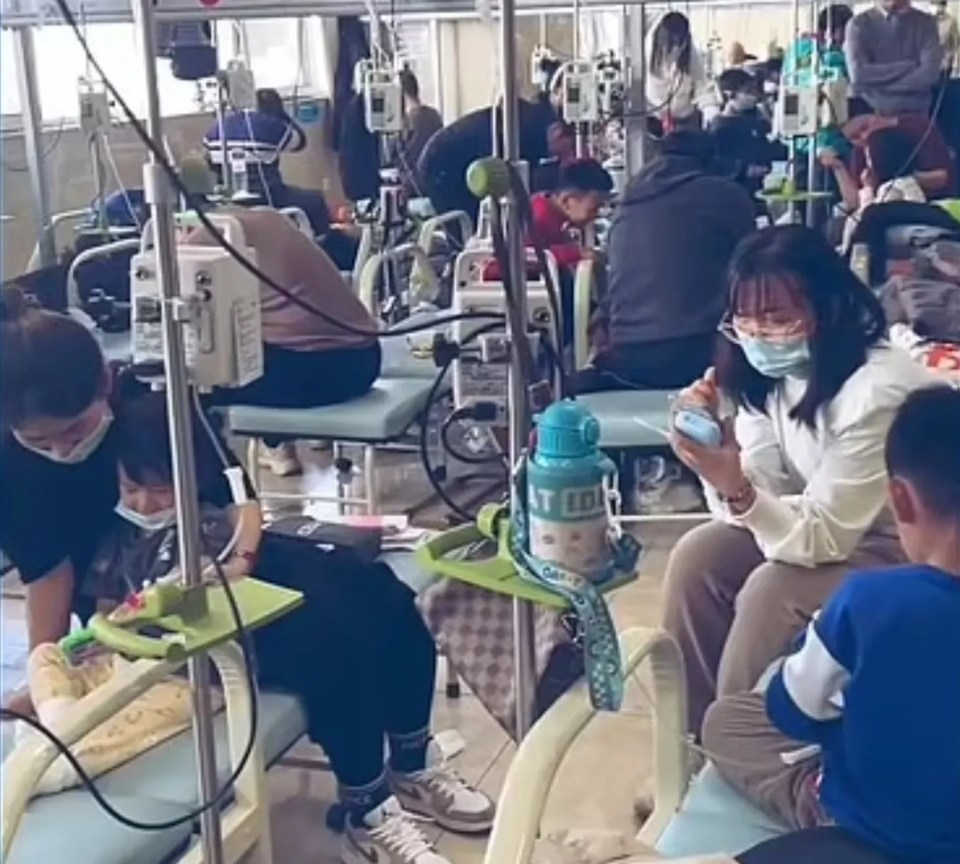 Overcrowded Chinese hospital ward with many patients receiving IV treatments.