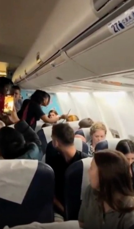 The footage shows a flight attendant appear with plastic restraints