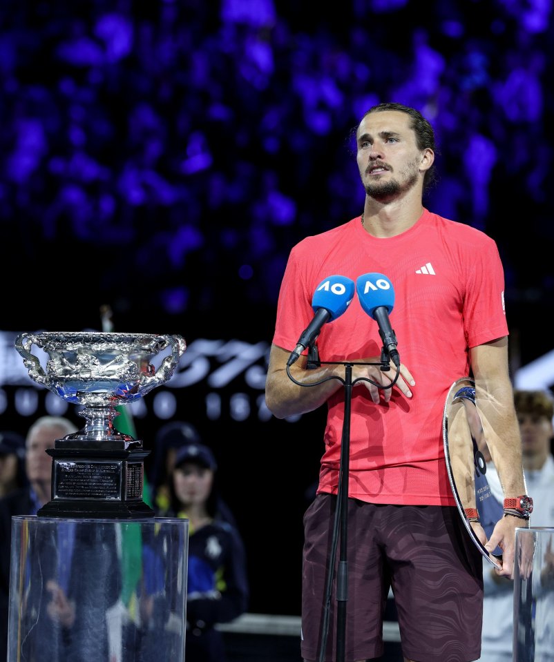 Alexander Zverev at an awards ceremony, holding a trophy and speaking into microphones.