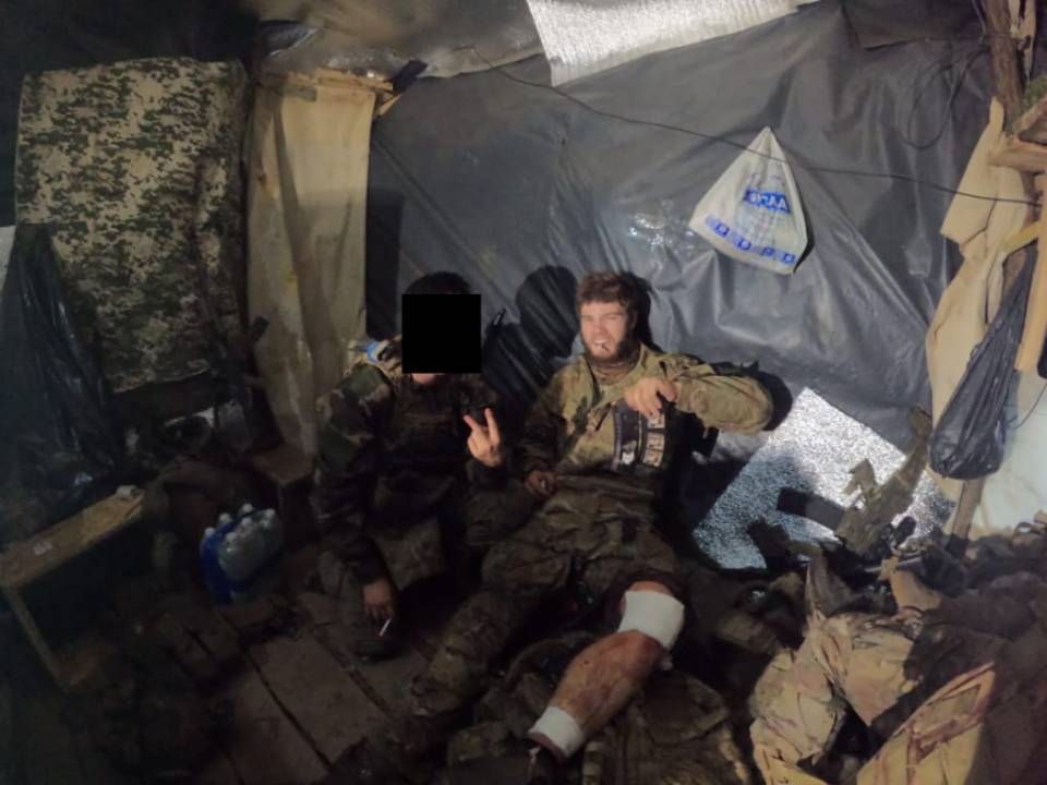 Photo of two soldiers in a makeshift shelter in Ukraine; one soldier's face is obscured.