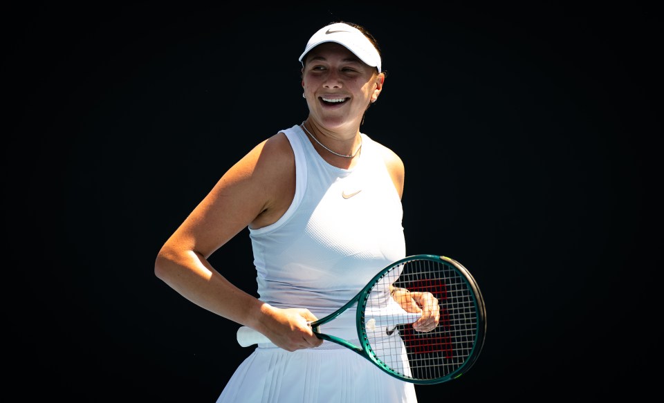 Amanda Anisimova smiling and holding a tennis racket.