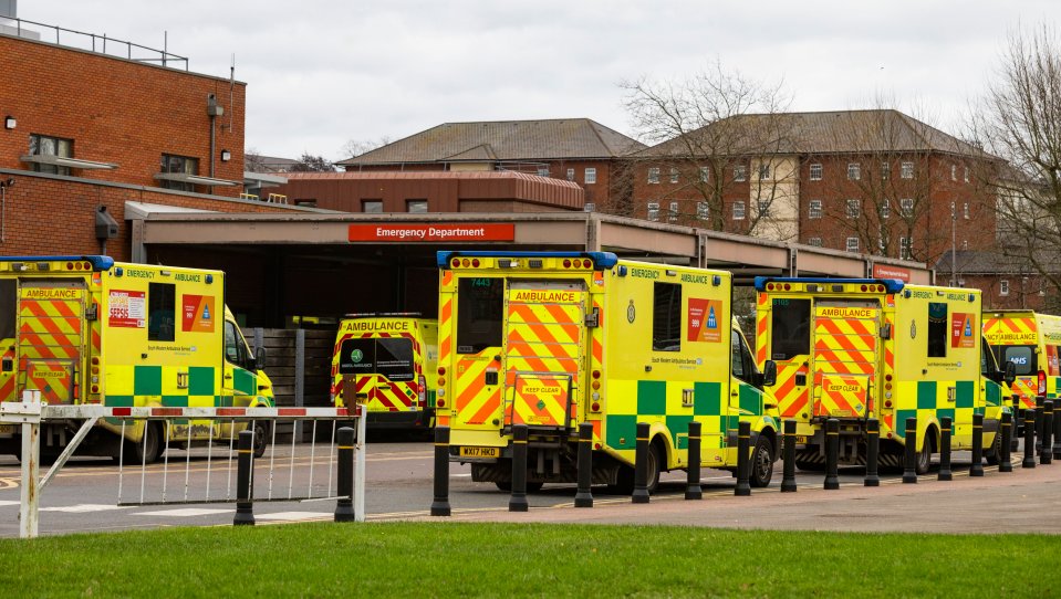 Multiple ambulances waiting outside a hospital emergency department.