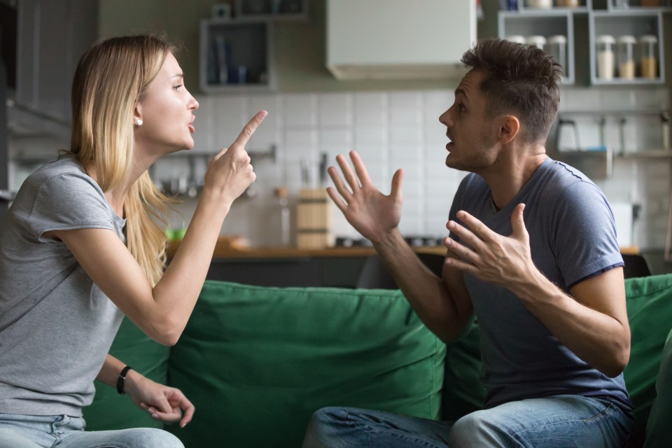 A couple angrily arguing on a couch.