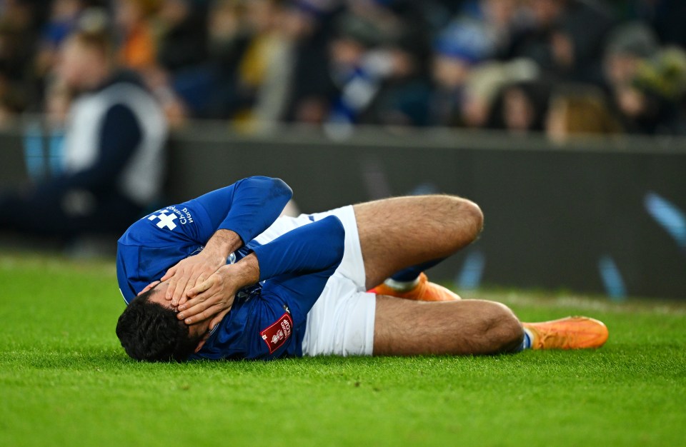 Soccer player Armando Broja on the ground, injured, face in hands.