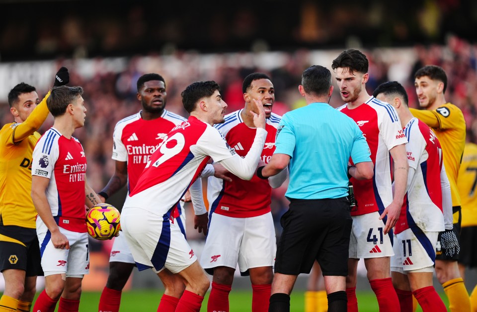 Arsenal players arguing with a referee.