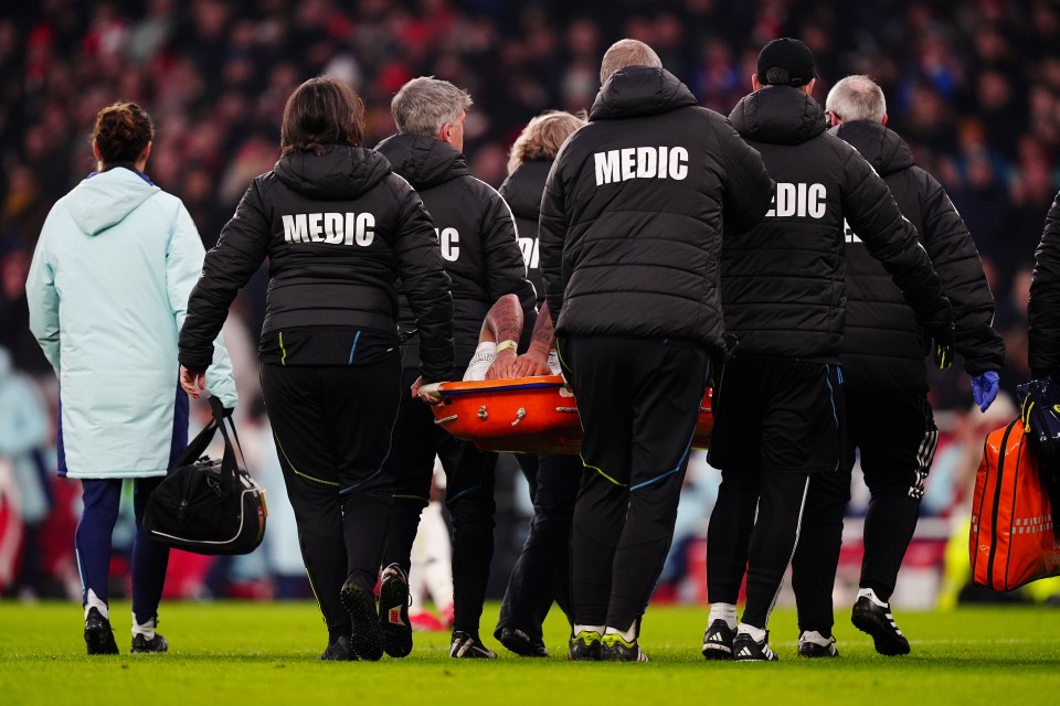 Injured soccer player being carried off the field on a stretcher by medical personnel.