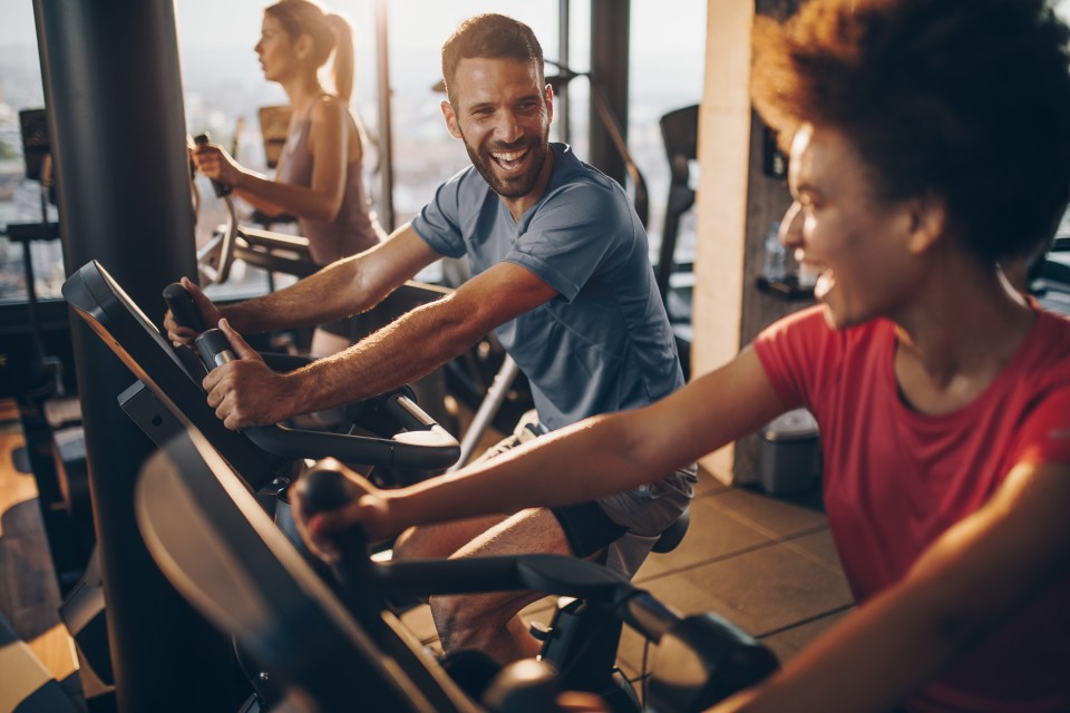 Three people exercising on stationary bikes at a gym.