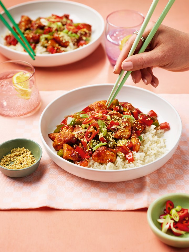 Sweet and sour chicken with rice, served with chopsticks.