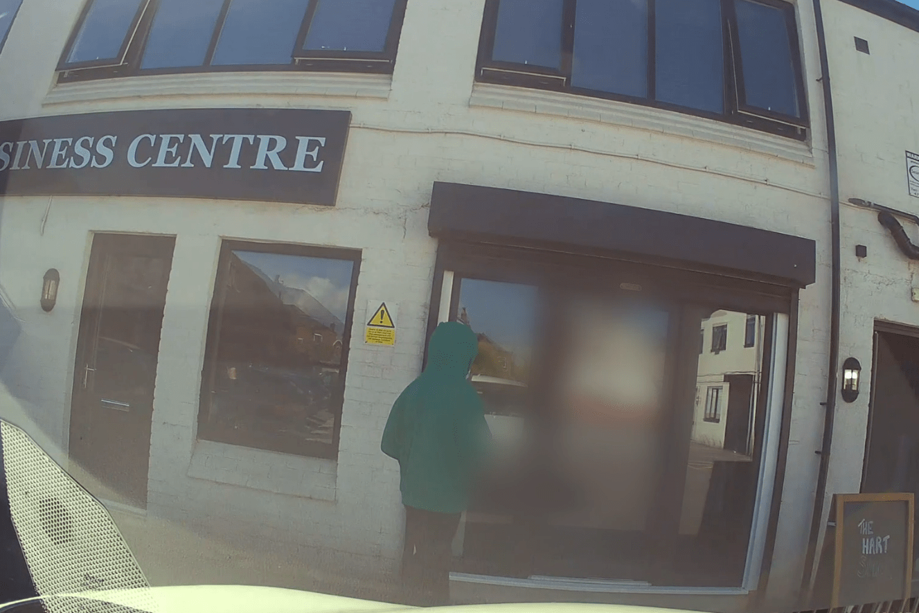 Person in a green hooded jacket standing outside a business center.