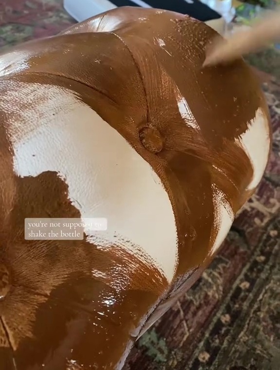 Brown paint being applied to a tufted sofa.