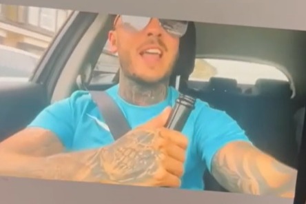 Man with tattoos speaking in a car.