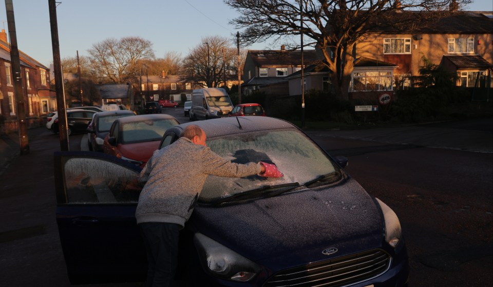 Motorists clear ice from their car windows in Whitley Bay, North Tyneside, this morning