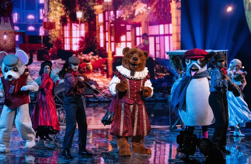 Costumed performers, including a bear and mouse, on a stage.