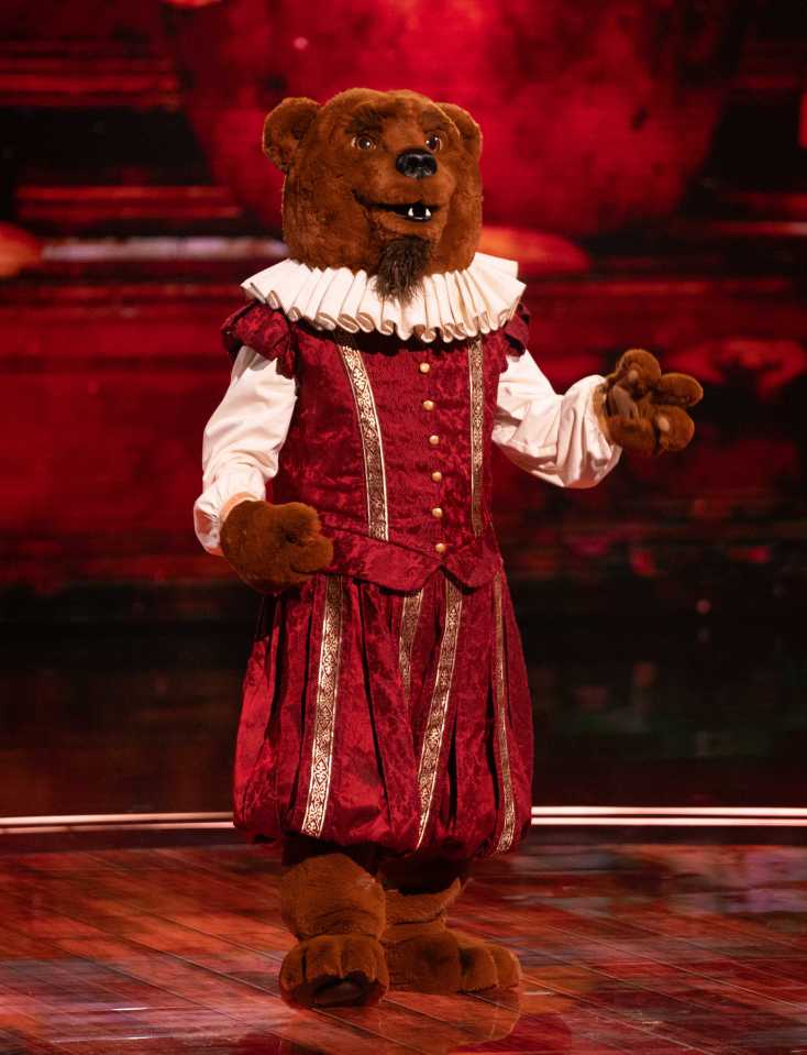 Bear in a red Renaissance-style costume on a stage.