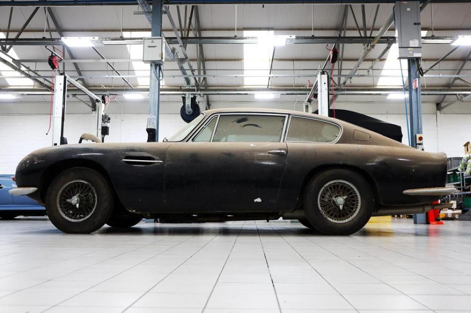 Dust-covered Aston Martin DB6 in a garage.