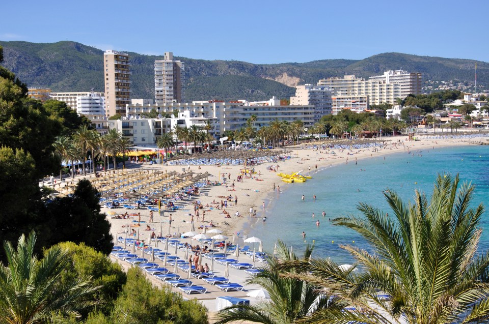 Beach view in Magaluf, Mallorca, with hotels and many people on the sand.