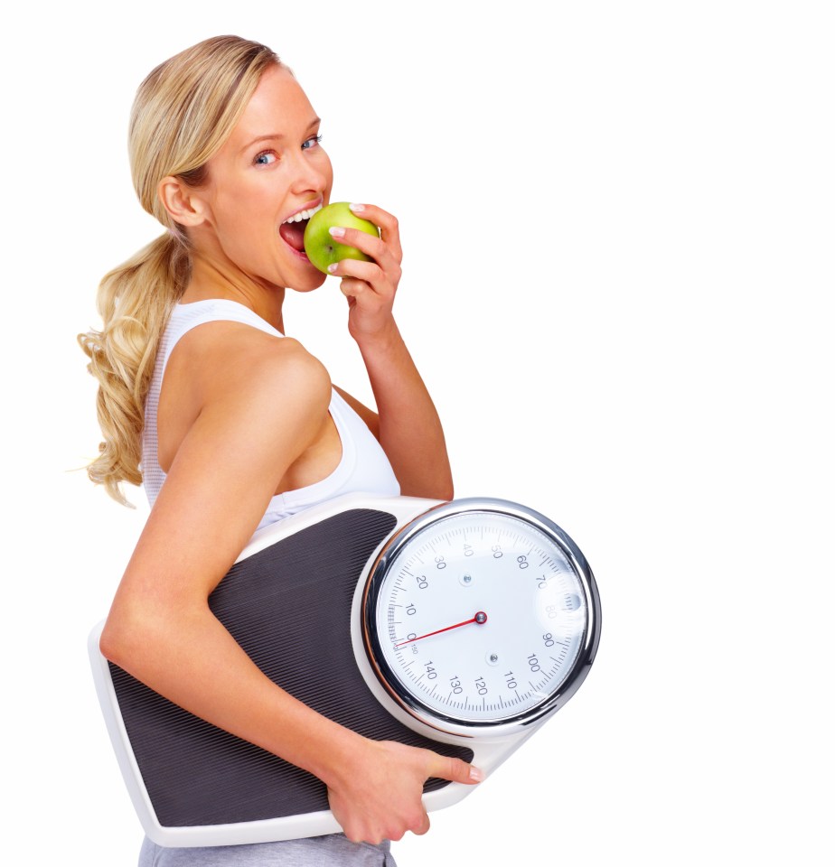 Woman holding a scale and eating an apple.