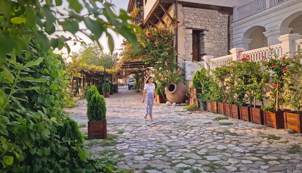 Woman walking down a cobblestone street in a historic town.