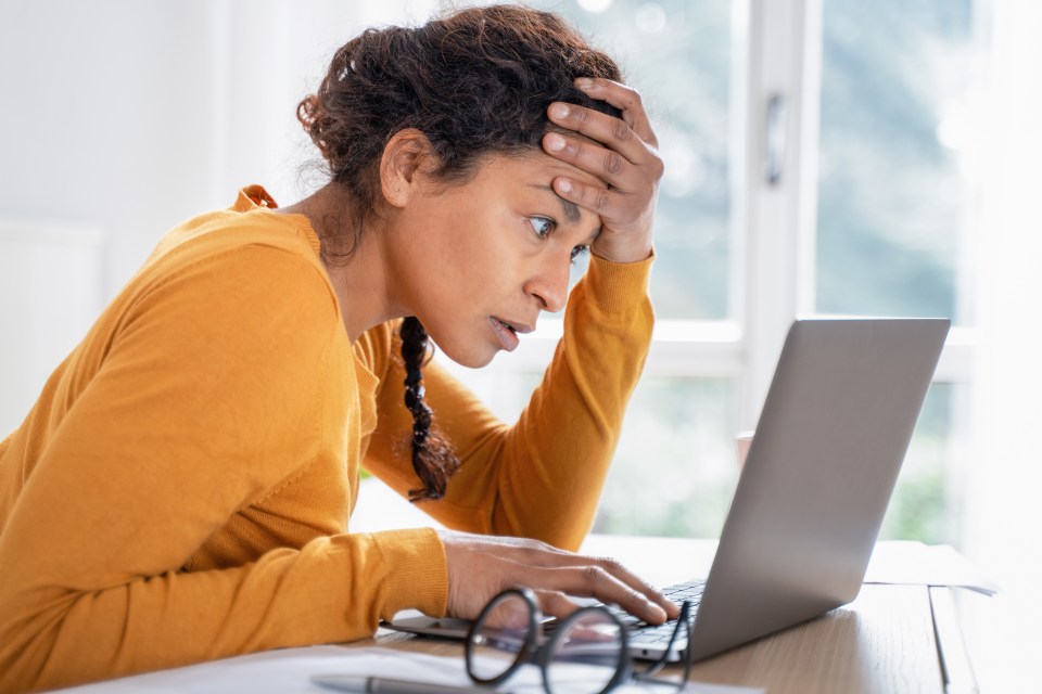 Worried woman reading bad news on her laptop.