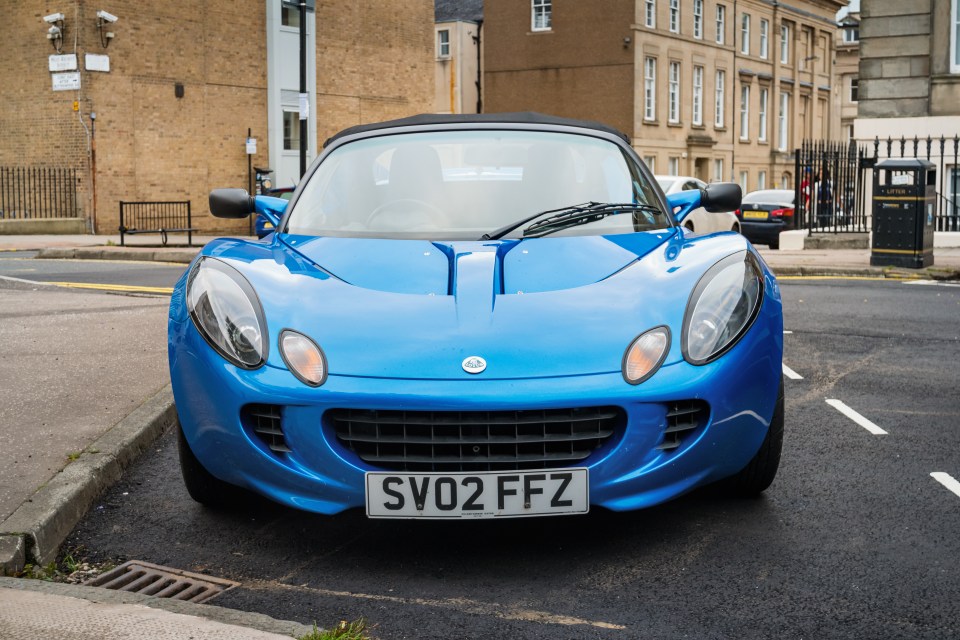 Blue Lotus Elise sports car parked on a street.