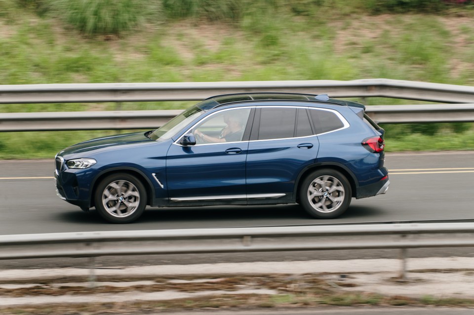 Blue BMW X3 driving on a highway.