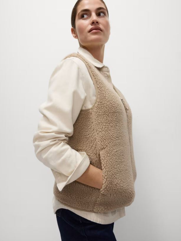 Woman wearing a beige borg gilet.