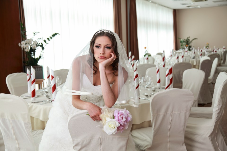 Sad bride in wedding dress sitting alone at a wedding reception.