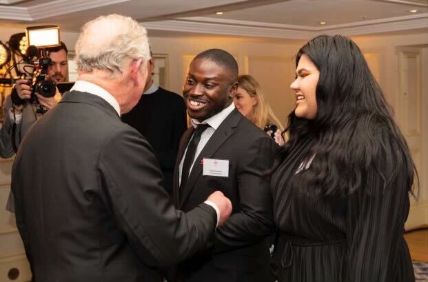 King Charles III shaking hands with a young man and woman at an event.