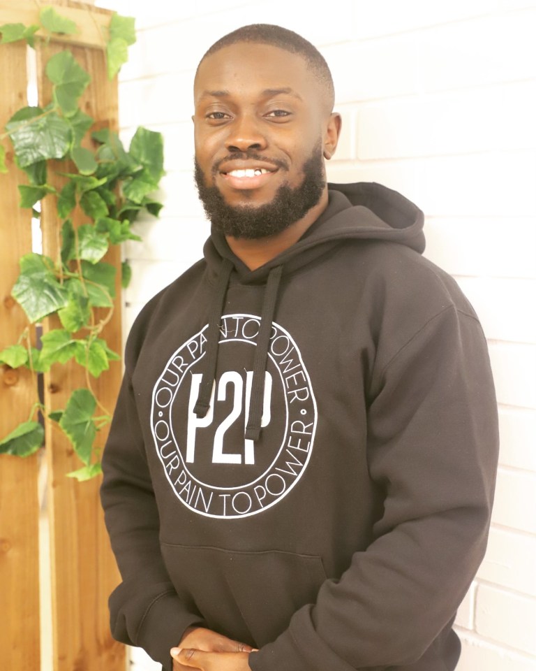 Man in black hoodie with "Our Pain to Power" logo.