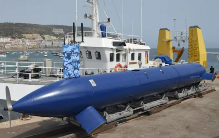 A large blue submarine drone on a transport vehicle.