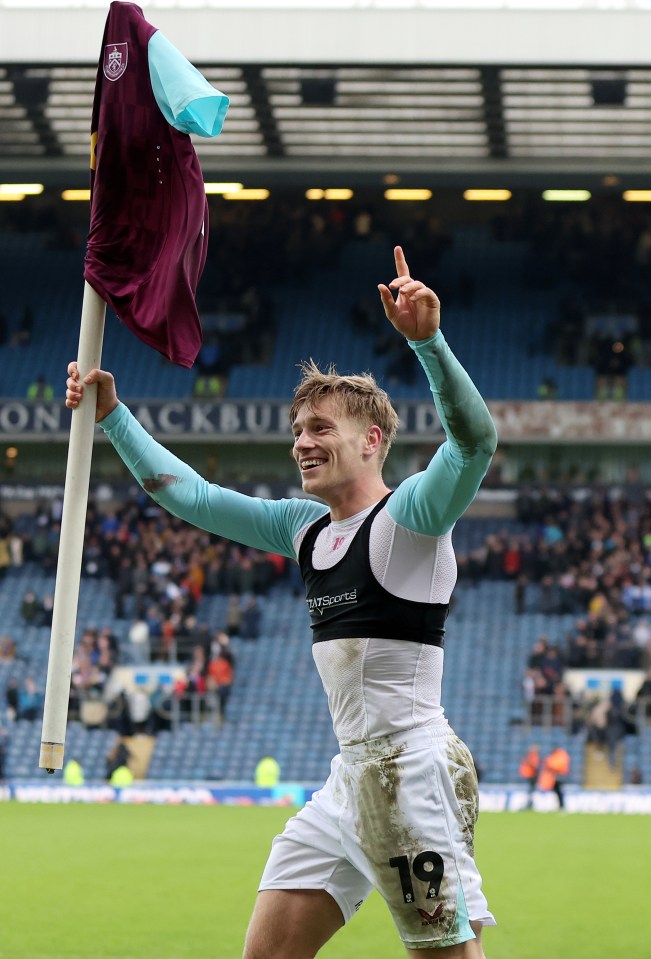 Zian Flemming celebrates a Burnley victory, holding a corner flag aloft.