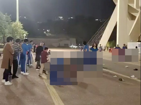 a group of people are gathered outside of a stadium at night