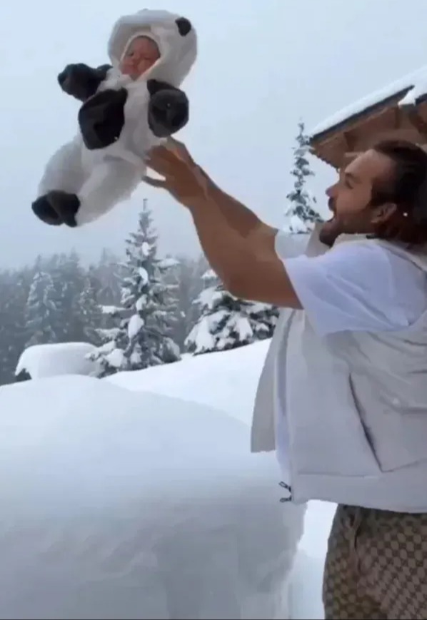 Man throwing baby in panda costume into snowdrift.