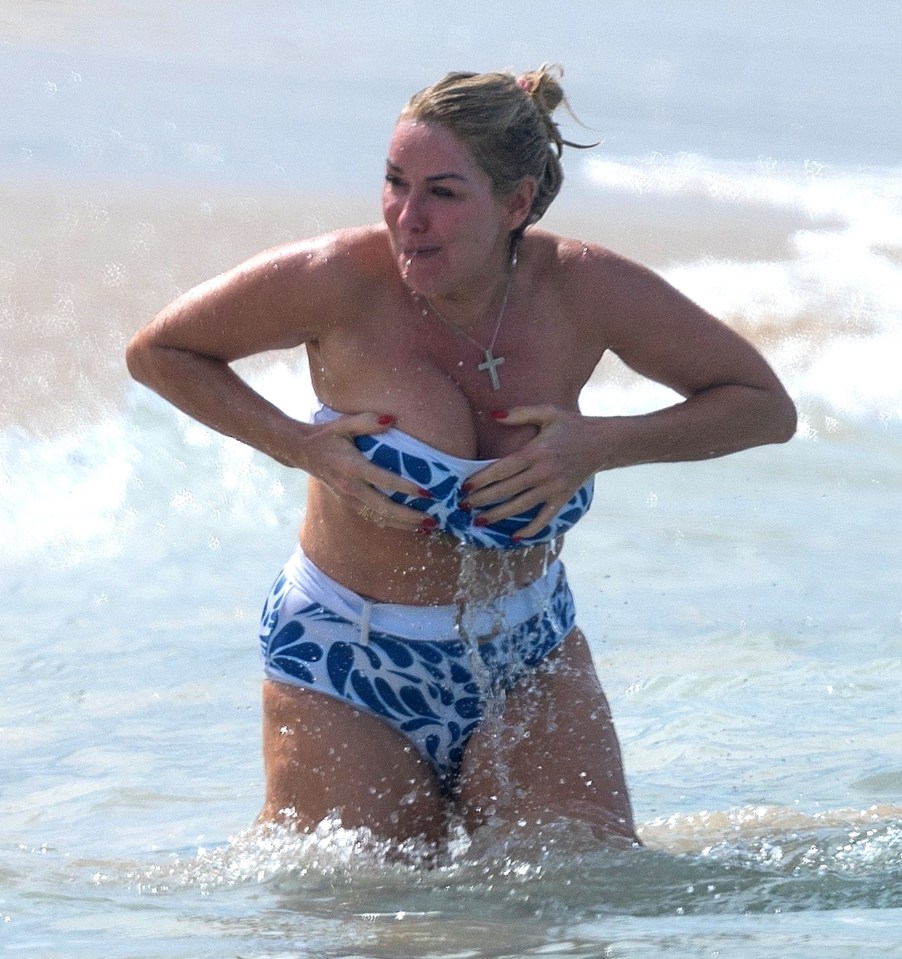 Claire Sweeney on a Barbados beach, adjusting her bikini top while entering the ocean.