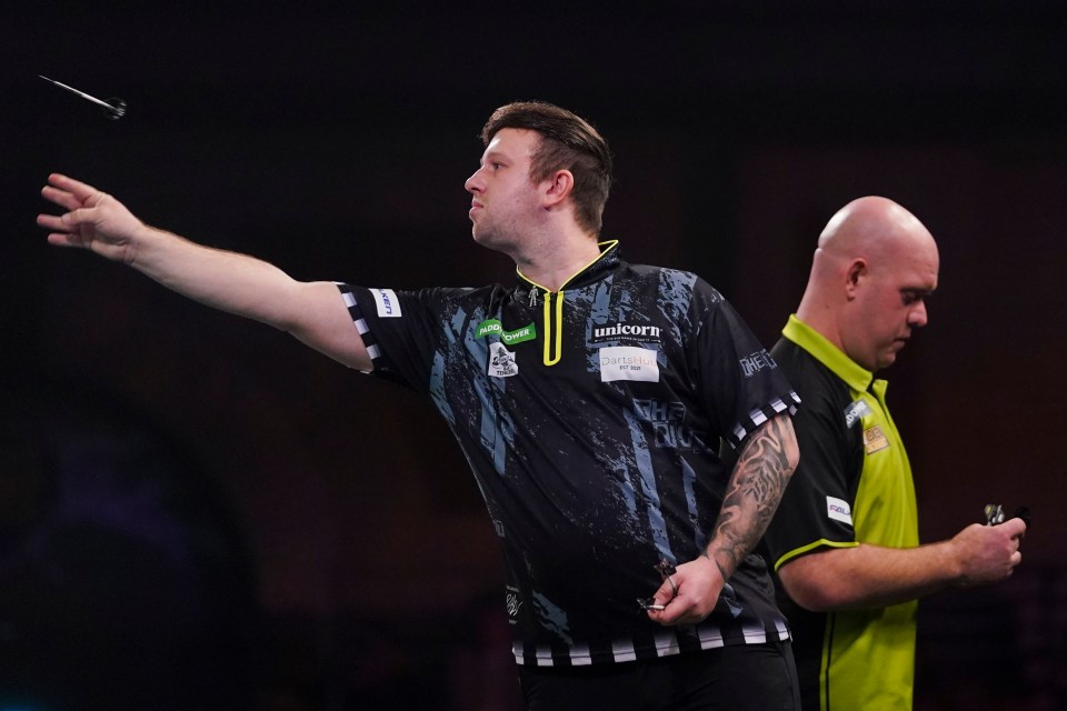 Callan Rydz throwing a dart during a darts match.