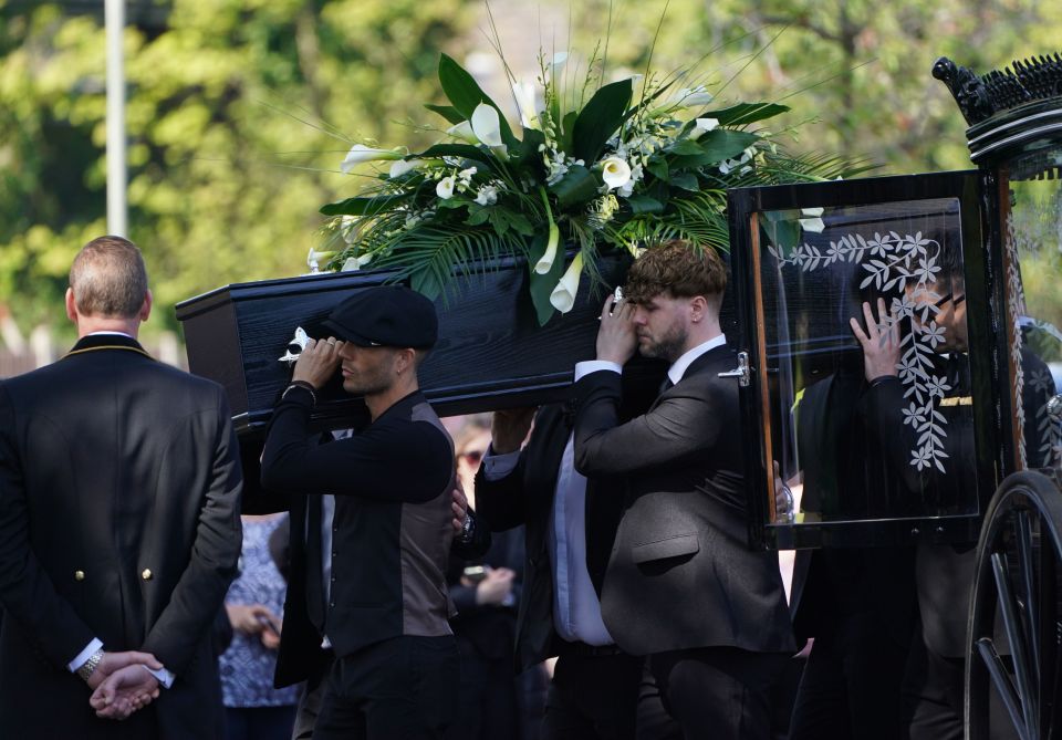 Pallbearers carrying a coffin at a funeral.