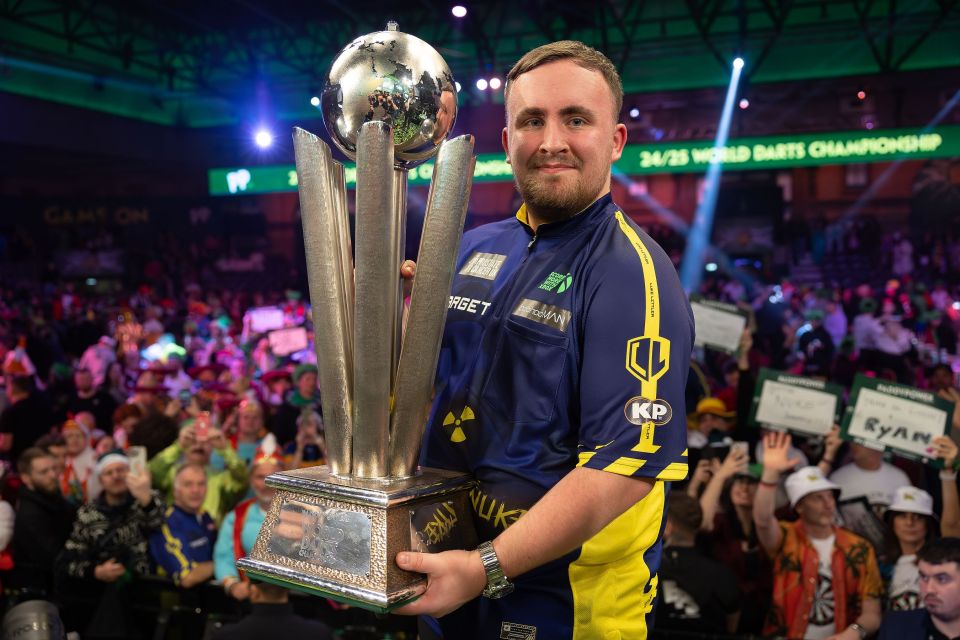 Luke Littler holding the Sid Waddell trophy after winning the World Darts Championship.