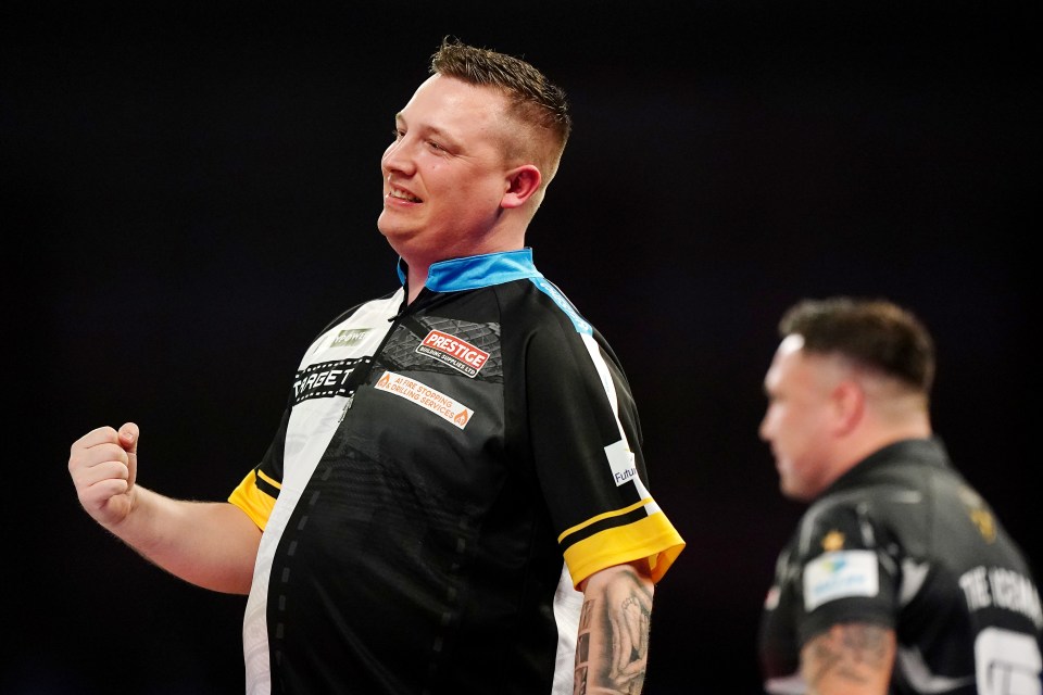 Chris Dobey celebrates winning a quarter-final darts match.