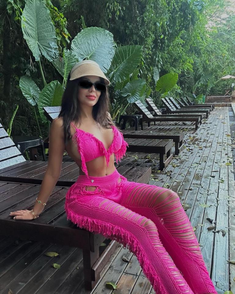 Woman in pink fringed outfit by the pool.