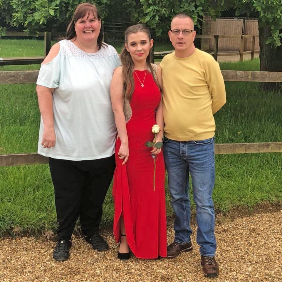 A woman in a red dress with her parents.