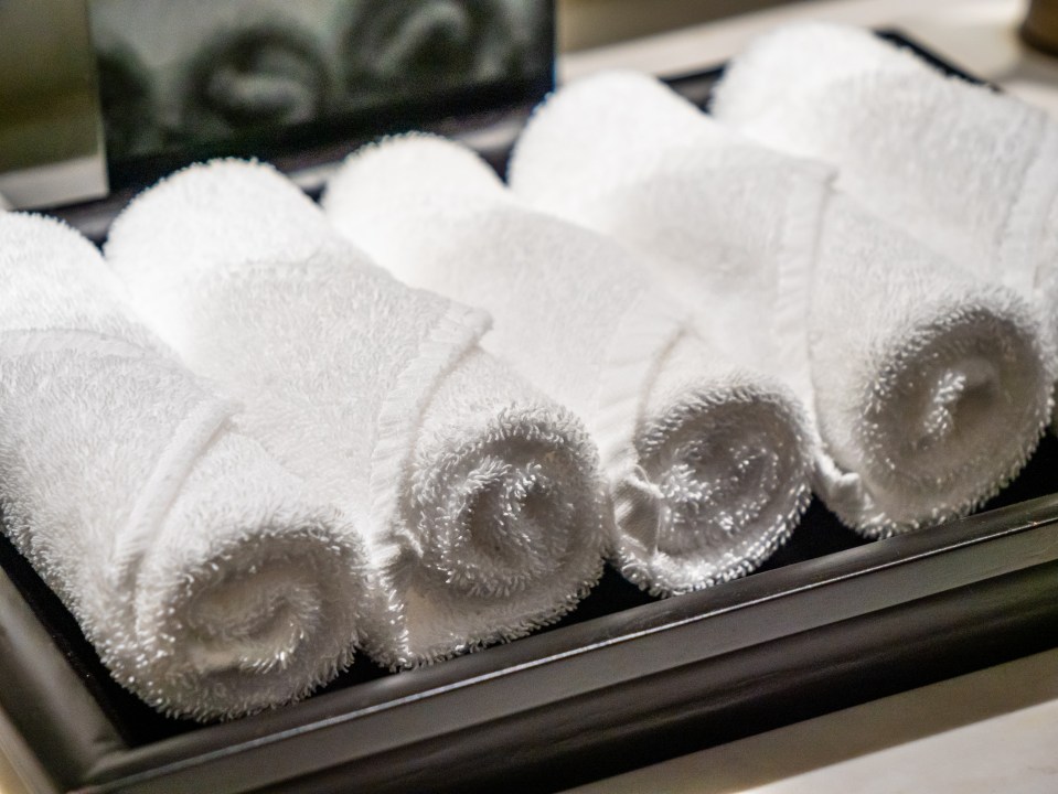 Rolled white towels on a tray.