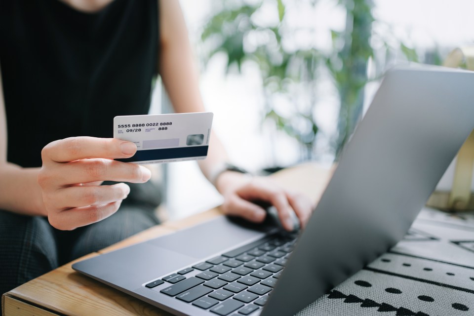 Woman using laptop to shop online and paying with credit card.