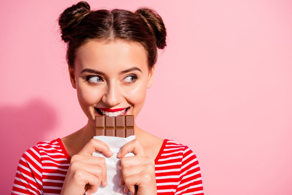 Woman biting into a chocolate bar.