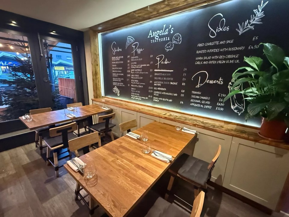 Angela's Trattoria interior showing tables set for diners and a chalkboard menu.