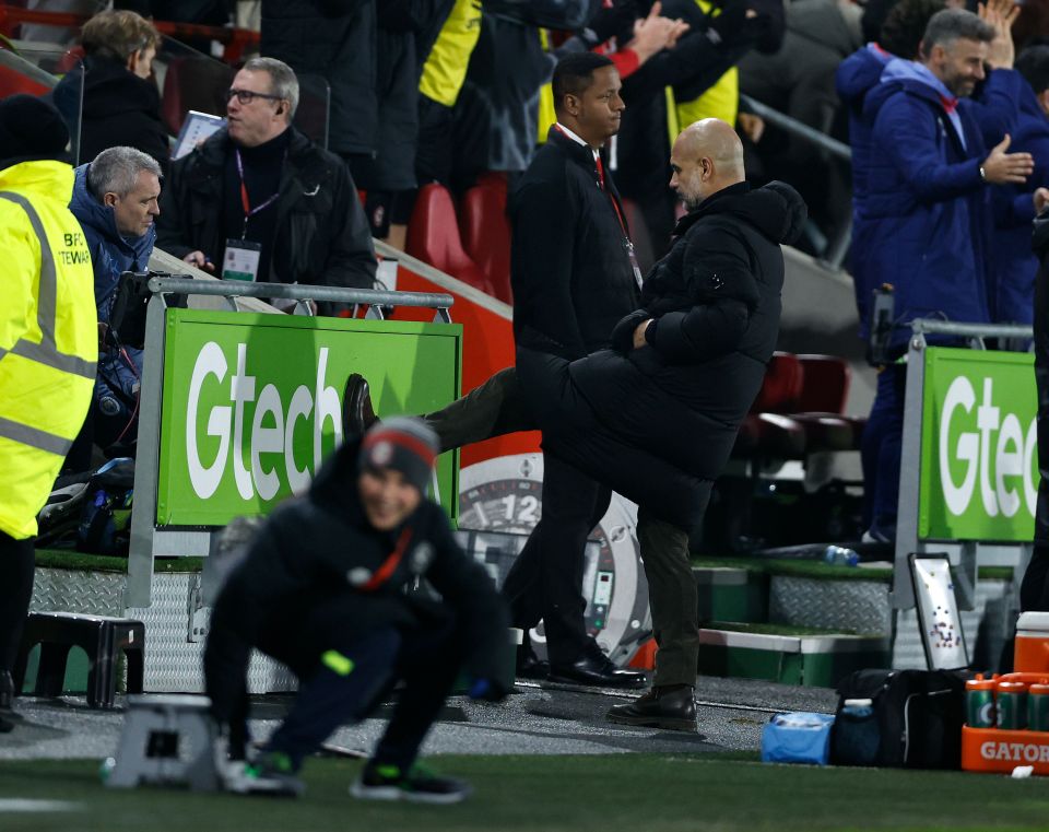 Pep Guardiola kicking an advertising board.