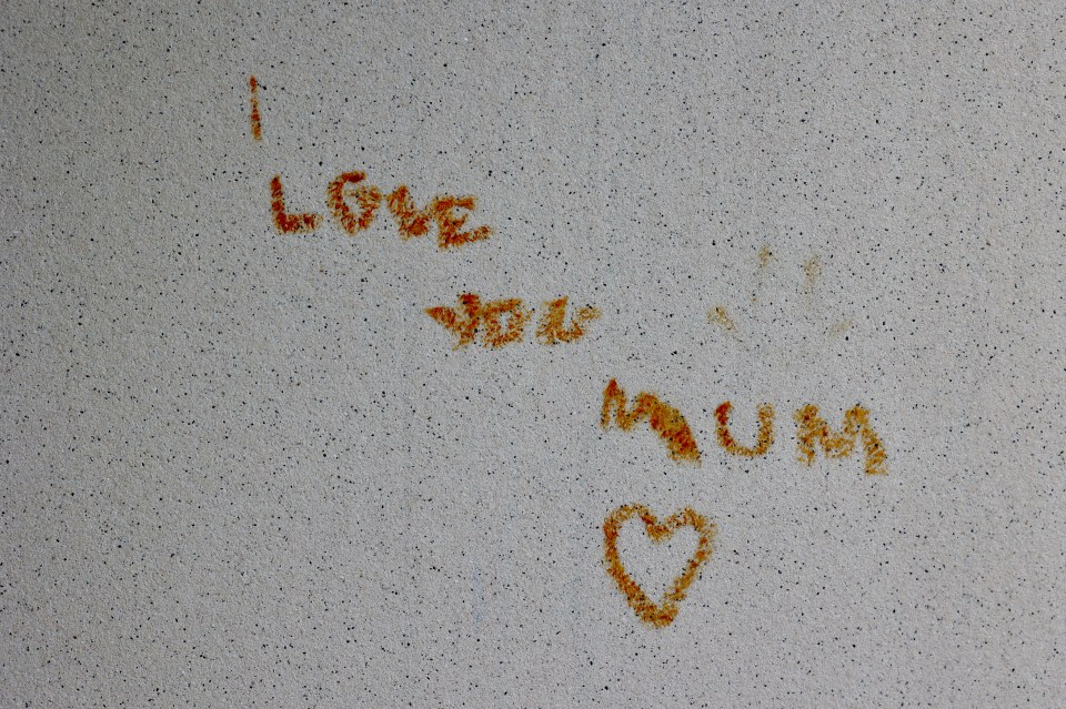 Rust-colored message on a wall: "I LOVE YOU MUM" with a heart.